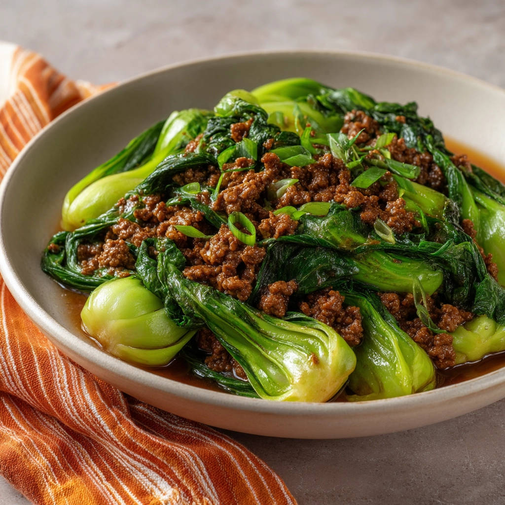 Beef and bok choy stir-fry served in a shallow bowl, a hearty portion topped with fresh green onions.