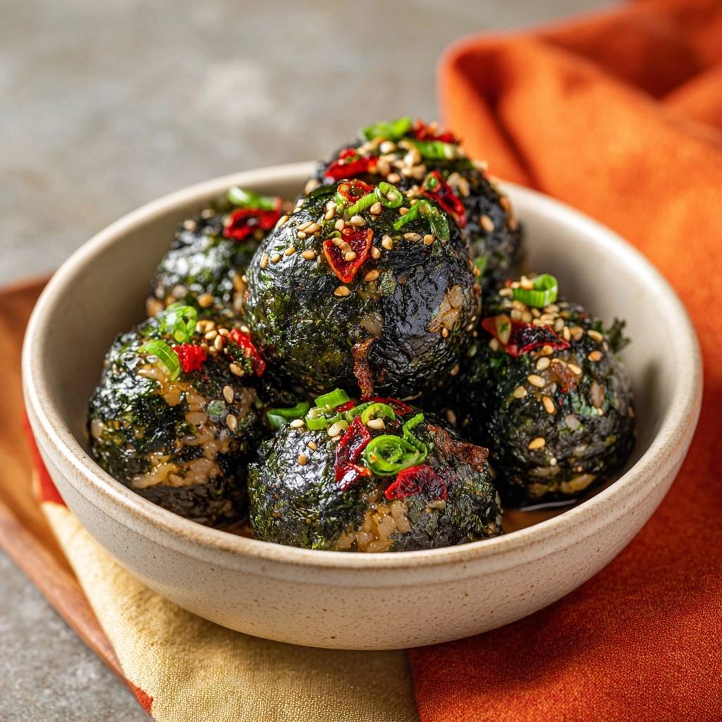 Spicy nori onigiri are presented in a bowl, showcasing their topping of sesame seeds, chili, and green onions.