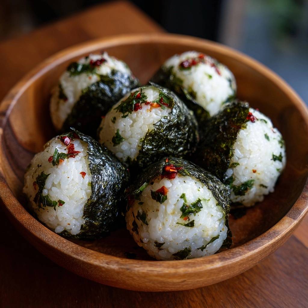Spicy nori onigiri arranged in a wooden bowl, sprinkled with chili flakes and parsley garnish.